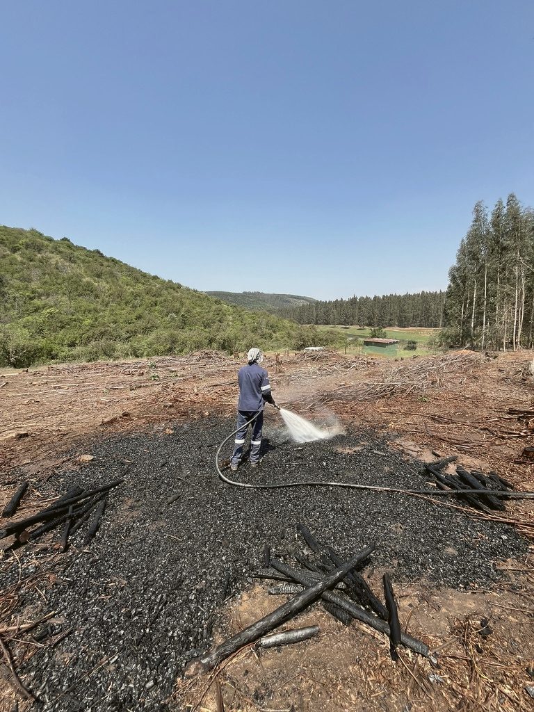 Crew member quenching a char bed with water